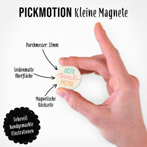 Eine Hand hält einen Magneten aus dem Pickmotion "Magnetische Familienbande" Set (5 Magnete S) mit "Home sweet home"-Text und liebevoller deutscher Deko.