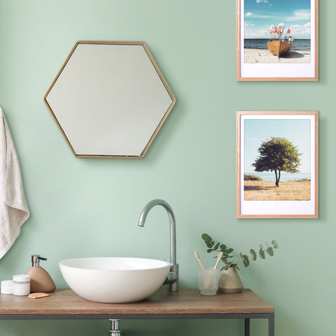 Minimalistisches Badezimmer mit einem sechseckigen Spiegel, einem runden Waschbecken und dem "stand tall"-Kunstposter von Pickmotion in einem maßgefertigten Bilderrahmen an einer mintgrünen Wand.