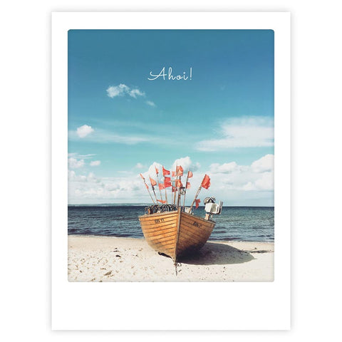 Ein Holzboot mit roten Flaggen an einem Sandstrand unter blauem Himmel, "time out ahoi" von Pickmotion, ist ein Kunstposter, das stilvollen Charakter in jeden Raum bringt.
