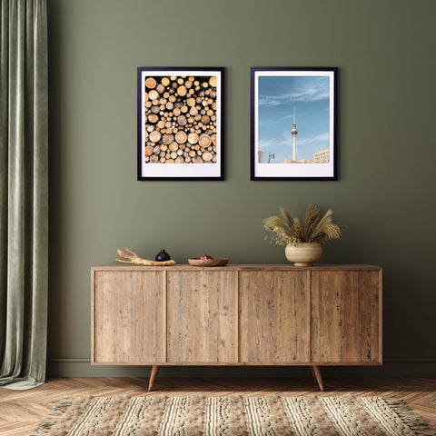 Gemütliches, modernes Wohnzimmer mit stilvollem Flair mit dem Kunstposter "take me to the woods" von Pickmotion, zwei maßgefertigten Bilderrahmen, einem hölzernen Sideboard mit Vase - alles vor einer grünen Wand.