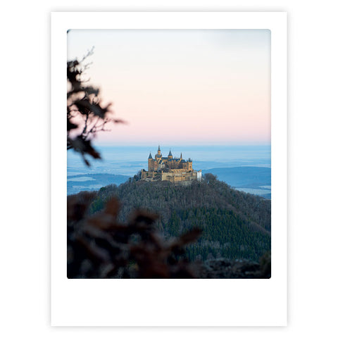 Das Kunstposter "Castle in the sky" von Pickmotion zeigt eine Burg auf einem Hügel inmitten von Bäumen und einem pastellfarbenen Himmel und verleiht jedem Raum einen stilvollen Charakter.