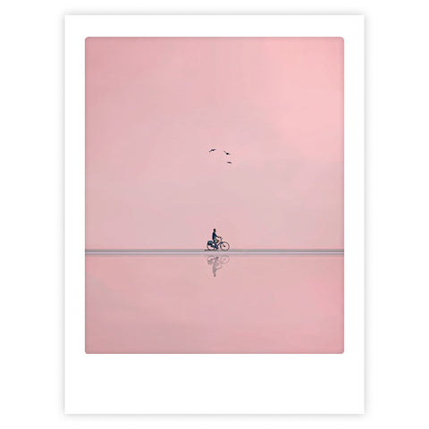 Eine stilvolle Figur fährt auf einem Fahrrad auf flachem Boden unter einem rosafarbenen Himmel mit drei Vögeln darüber und verkörpert so den Geist des Pickmotion Art Posters "ride on".