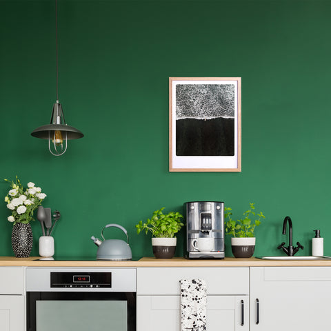 Moderne Küche mit grüner Wand, Kaffeemaschine, Wasserkocher, Pflanzen und Pickmotion "black beach" Art Poster in einem maßgefertigten Bilderrahmen über schlichten weißen Schränken - gestylt für einen internationalen Instagram-Look.