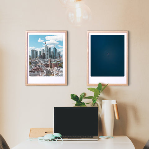 Zwei gerahmte "the big blue" Art Poster Prints von Pickmotion verleihen einem Schreibtisch mit Laptop, Lampe und Pflanze an einer beigen Wand einen stilvollen Charakter.