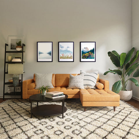 Ein gemütliches Wohnzimmer mit einer hellbraunen Couch, einem gemusterten Teppich, Pflanzen und dem Kunstposter "So weit das Auge reicht" von Pickmotion in einem maßgefertigten Rahmen an der Wand.