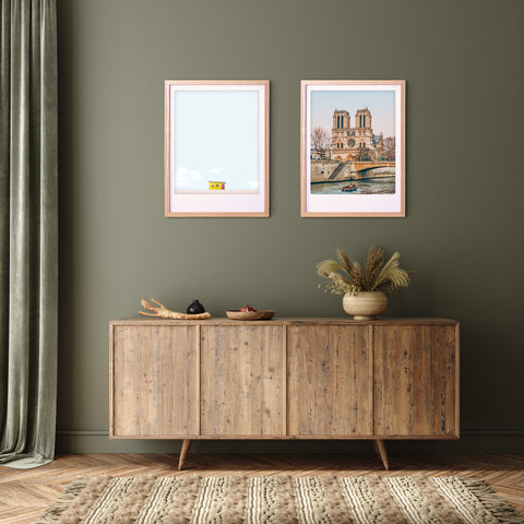 Ein hölzernes Sideboard mit Dekoration steht an einer grünen Wand, darunter zwei gerahmte Kunstplakate "Eine Kreuzfahrt auf der Seine" von Pickmotion.