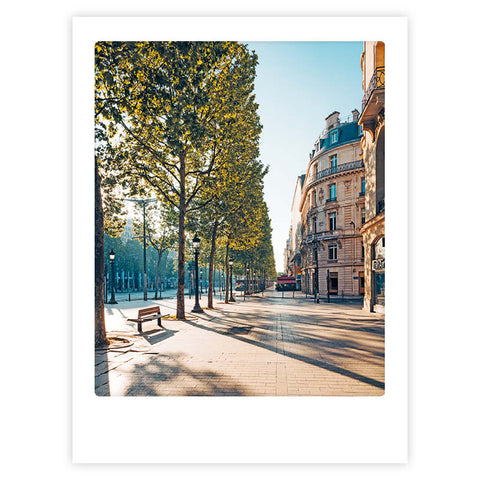 Bringen Sie stilvollen Charakter in jeden Raum mit dem "a sunny day in paris" Kunstposter von Pickmotion, das eine von Bäumen gesäumte Straße, klassische europäische Gebäude, Bänke und den Charme eines hellen Pariser Morgens zeigt.