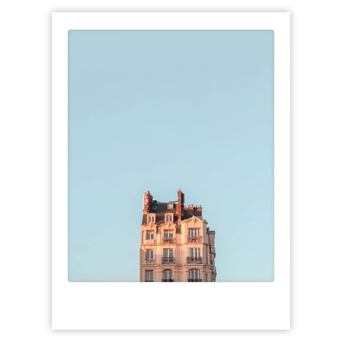 Das Pickmotion Art Poster "blue sky in paris" zeigt ein sonnenbeschienenes Wohnhaus mit Schornsteinen unter einem klaren blauen Himmel, eingerahmt in einen weißen Bilderrahmen für stilvollen Charakter.