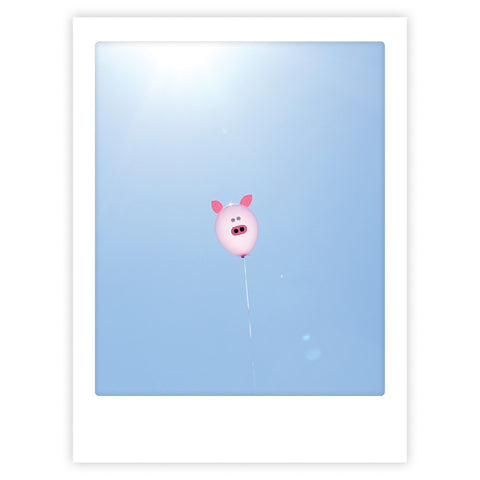 Ein Pickmotion "Ballonschwein" - ein rosafarbener, schweinchenförmiger Ballon mit stilvollem Charakter - schwebt vor einem klaren blauen Himmel mit Sonnenlicht oben links. Perfekt für ein Kunstposter.
