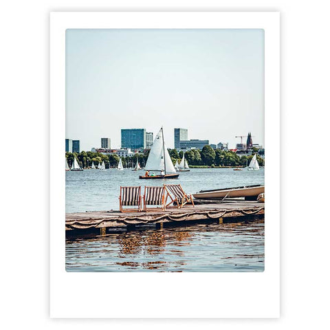 Das "great view" Art Poster von Pickmotion zeigt ein Segelboot auf einem See mit angedockten Booten und einer Stadtskyline - der perfekte stilvolle Charakter für Ihre Wände.