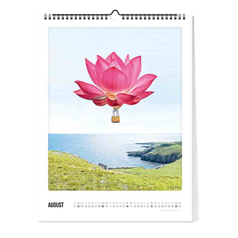 Ein rosafarbener, lotusförmiger Heißluftballon schwebt über einer grasbewachsenen Klippe am Meer, abgebildet auf der Augustseite des Pickmotion "Zauberhafte Welt" Kalenders (Format 30x40).