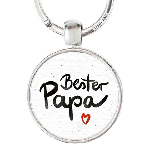 Runder Edelstahl-Schlüsselanhänger von Pickmotion mit "bester Papa" und kleinem roten Herz als Reliefdruck, stilvoll in Schwarz auf weißem Hintergrund gestaltet.