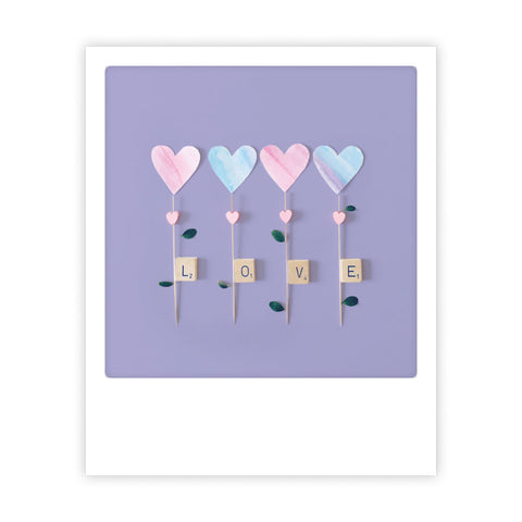 Vier pastellfarbene Herzchen und Scrabble-Kacheln mit dem Schriftzug LOVE auf lilafarbenem Hintergrund - die Postkarte "purple love" von pickmotion ist perfekt für Sofortbild-Fans oder Instagram-Fotografen, die den Sofortbild-Stil schätzen.