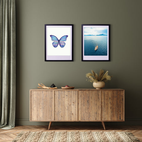 Ein hölzernes Sideboard unter zwei Pickmotion-Rahmen "spread your wings and fly" - einer zeigt einen Schmetterling, der andere ein Boot auf dem Wasser - verleiht der grünen Wand einen stilvollen Charakter.