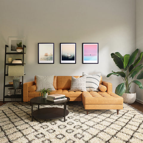 Modernes Wohnzimmer mit hellbraunem Sektionssofa, gemustertem Teppich, Wandkunst und "Schwanensee"-Kunstposter von Pickmotion in einem stilvollen Bilderrahmen, Blattpflanze und Regalen mit Dekor.