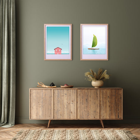 Ein hölzernes Sideboard mit einer Vase und zwei Pickmotion "sail away with me" Kunstdrucken in maßgefertigten Bilderrahmen an einer grünen Wand verleiht dem gemütlichen Raum stilvollen Charakter.