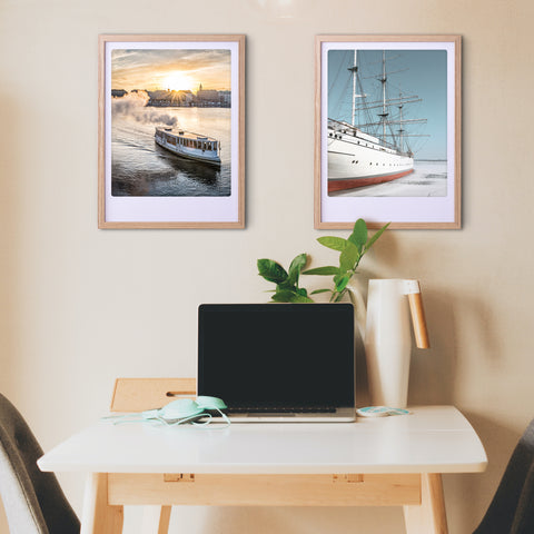 Ein Schreibtisch mit Laptop, Kopfhörern und zwei "sail with me"-Kunstpostern von Pickmotion - die an die beliebten maßgefertigten Bilderrahmen von internationalen Instagrammer*innen erinnern - an der Wand darüber.