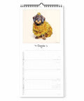 Ein in goldenes Lametta gehüllter Welpe sitzt unter einem Stern auf der Dezember-Seite des Pickmotion Bunter Hund - Familienplaner (Format 20x42), perfekt für Hundefreunde.