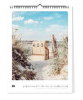 Ein Strandkorb mit der Aufschrift 865 sitzt im Sand zwischen Gräsern unter einem blauen Himmel - ideal für Liebhaber des Küste & Meer - Kalender (Format 30x40) von Pickmotion.