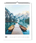 Das Bild "Der Berg ruft - Kalender" (30x40) von Pickmotion zeigt hölzerne Anlegestellen mit Ruderbooten auf einem ruhigen Bergsee, umringt von schneebedeckten Gipfeln im Vorfrühling.