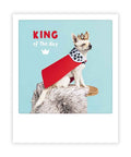 Ein kleiner Hund mit Krone und rotem Umhang sitzt auf einem Hocker auf dieser Pickmotion-Postkarte "König des Tages", die wie ein Sofortfoto gestaltet ist und den Text KÖNIG des Tages auf blauem Hintergrund zeigt - perfekt für Instagram-Fotos.